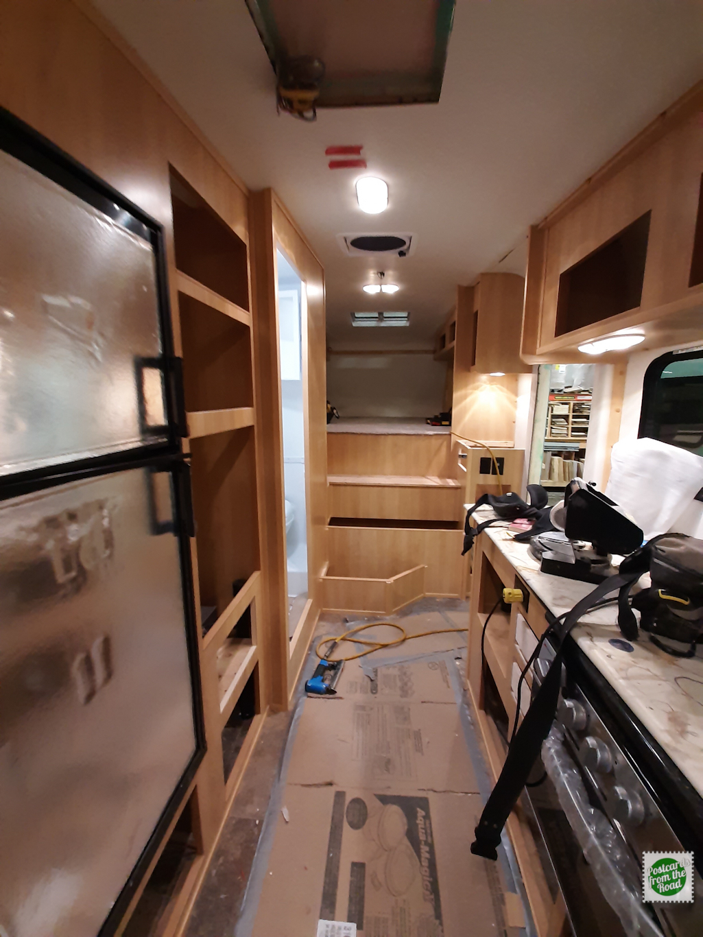 The oven is in the foreground on the right. The refrigerator, flush mount stovetop &amp; formica counter top all still have the protective covering in place. The ceiling Maxx Fan has been added – it&#039;s visible betweent the two ceiling lights.